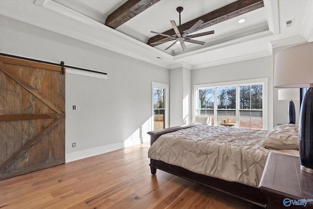 bedroom featuring beam ceiling, crown molding, light wood-type flooring, ceiling fan, and a barn door
