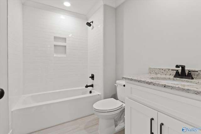full bathroom featuring vanity, hardwood / wood-style flooring, tiled shower / bath combo, and toilet