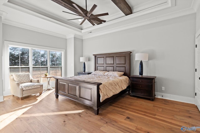 bedroom featuring crown molding, ceiling fan, beam ceiling, a tray ceiling, and light wood-type flooring