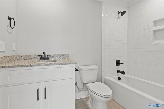 full bathroom featuring tiled shower / bath combo, vanity, hardwood / wood-style floors, and toilet