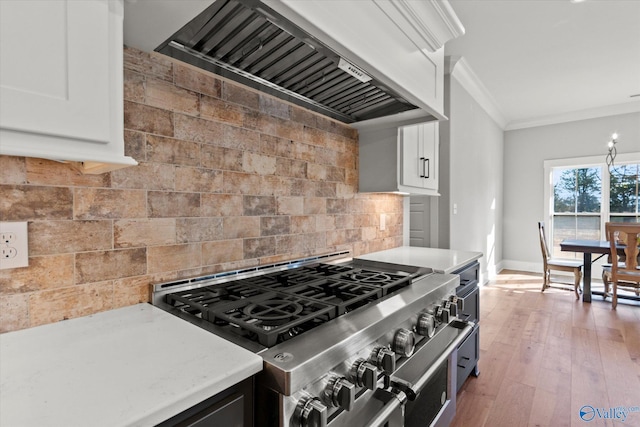 kitchen with premium range hood, crown molding, high end stainless steel range oven, decorative backsplash, and white cabinets