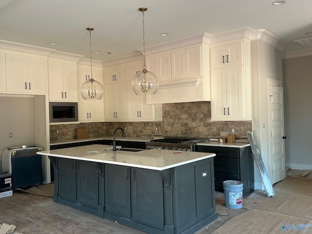 kitchen with sink, white cabinetry, hanging light fixtures, an island with sink, and built in microwave