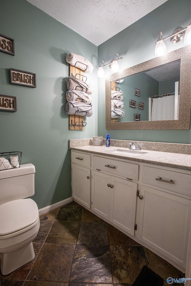 bathroom featuring vanity, a textured ceiling, and toilet