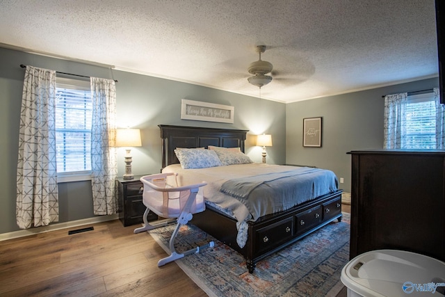 bedroom with crown molding, hardwood / wood-style floors, a textured ceiling, and ceiling fan