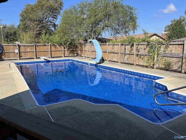 view of pool with a water slide and a diving board