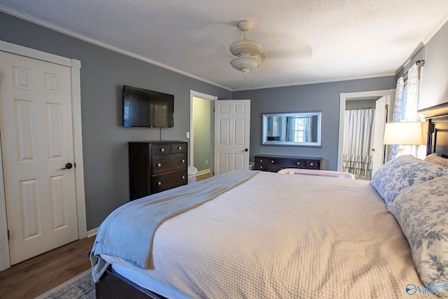 bedroom with ceiling fan, ornamental molding, wood-type flooring, and a textured ceiling