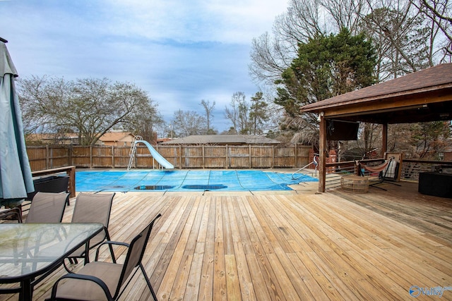 view of swimming pool with a gazebo, a water slide, and a deck