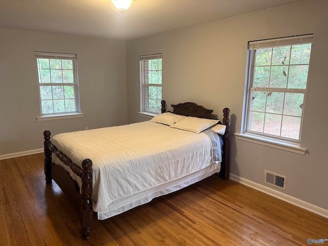 bedroom with dark hardwood / wood-style flooring and multiple windows