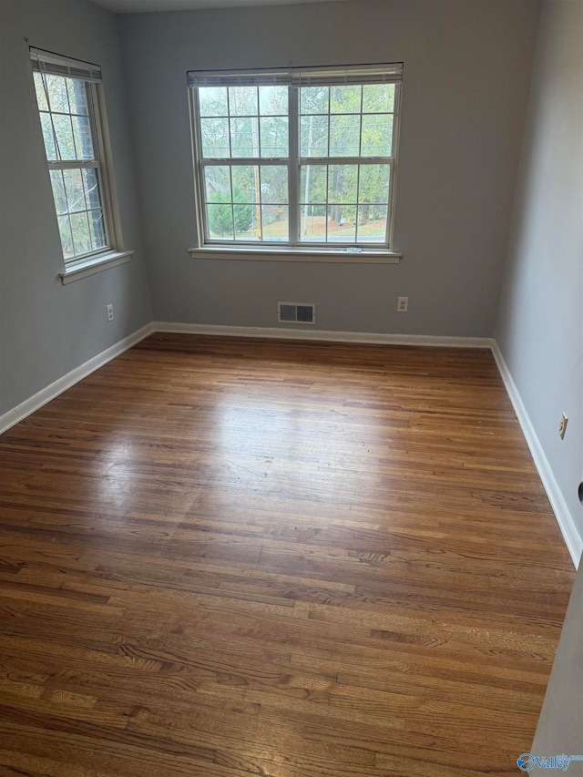 unfurnished room with a wealth of natural light and dark hardwood / wood-style floors