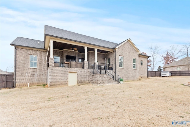 back of property with a yard and ceiling fan