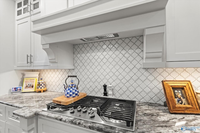 kitchen featuring stainless steel gas stovetop, white cabinetry, light stone countertops, and tasteful backsplash