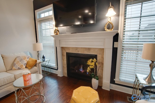 living room with a tiled fireplace and dark hardwood / wood-style flooring