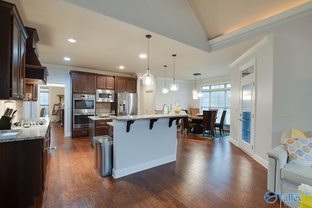 kitchen with a center island, dark hardwood / wood-style flooring, pendant lighting, a kitchen bar, and appliances with stainless steel finishes