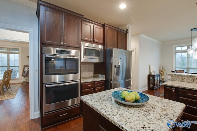 kitchen featuring light stone countertops, appliances with stainless steel finishes, crown molding, and dark wood-type flooring