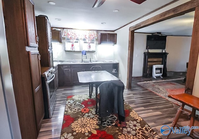 kitchen with stainless steel electric range, dark wood-type flooring, crown molding, ceiling fan, and dark brown cabinetry