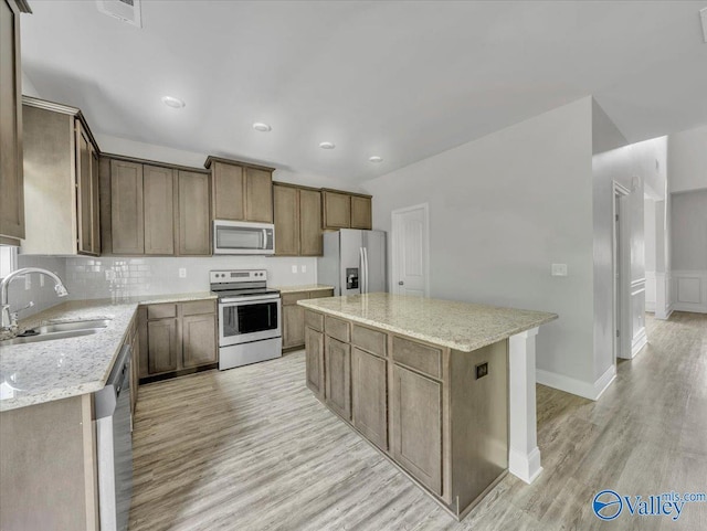 kitchen featuring light wood-style flooring, a sink, appliances with stainless steel finishes, and a kitchen island