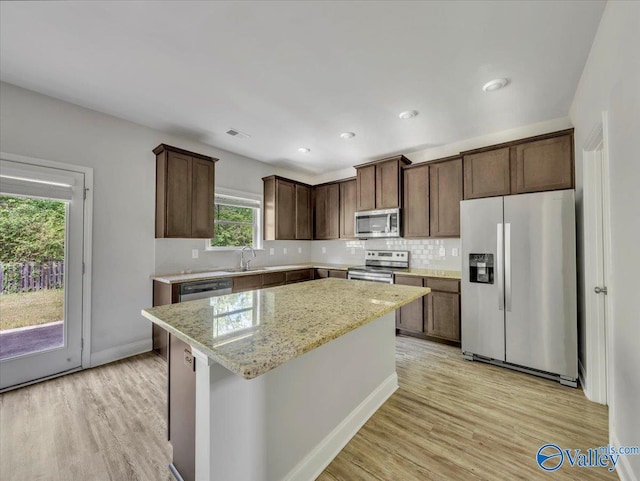 kitchen featuring visible vents, a sink, a center island, dark brown cabinetry, and appliances with stainless steel finishes