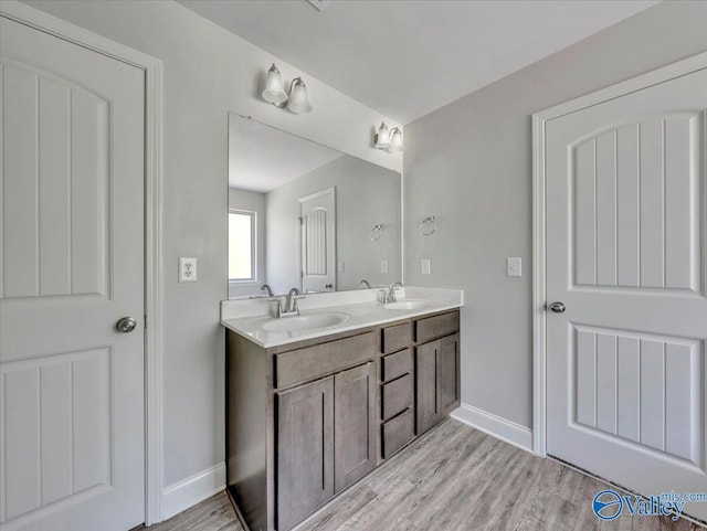 full bath with double vanity, baseboards, and a sink
