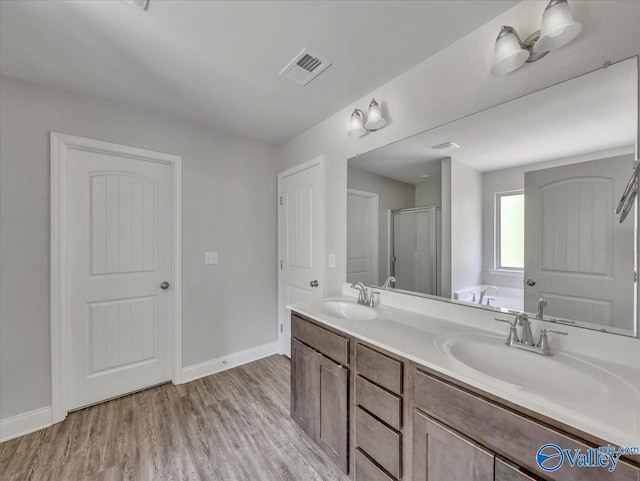 full bathroom with a shower stall, visible vents, wood finished floors, and a sink