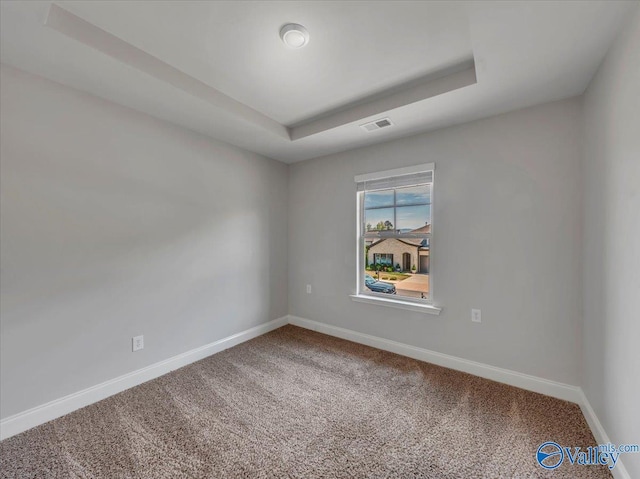 carpeted empty room with baseboards, visible vents, and a raised ceiling