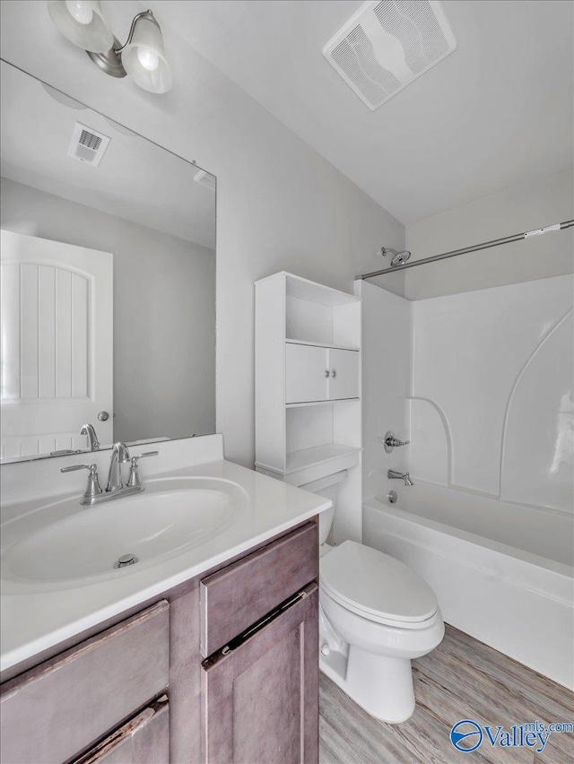 bathroom with toilet, vanity, wood finished floors, and visible vents