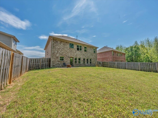 rear view of property featuring a fenced backyard, brick siding, and a yard