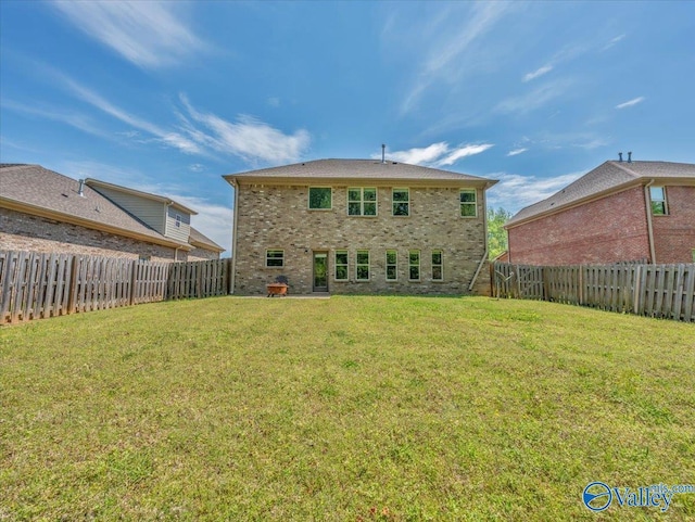 rear view of house featuring a lawn, a fenced backyard, and brick siding