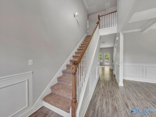 staircase featuring crown molding, wood finished floors, and visible vents