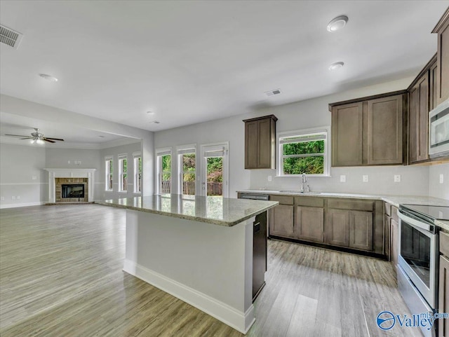 kitchen featuring stainless steel appliances, a ceiling fan, a sink, and light wood-style floors