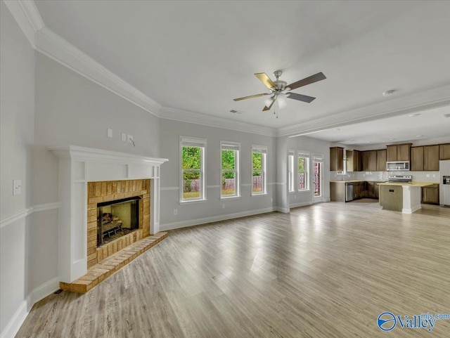 unfurnished living room featuring ceiling fan, baseboards, crown molding, and light wood-type flooring