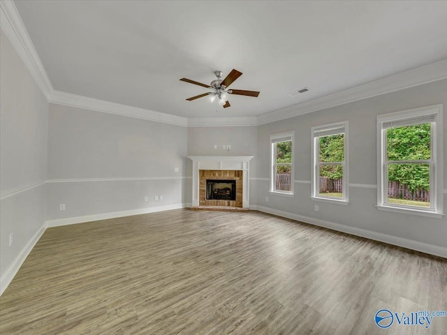unfurnished living room with wood finished floors, visible vents, a ceiling fan, baseboards, and a tiled fireplace