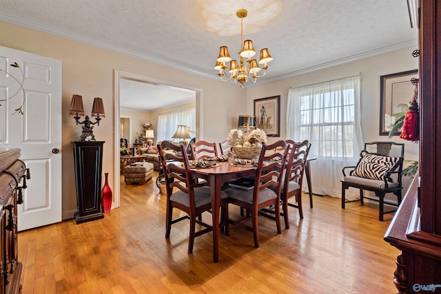 dining space with light wood-type flooring, a textured ceiling, an inviting chandelier, and ornamental molding