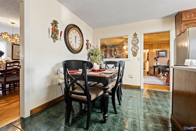 dining space with a chandelier, wood walls, dark wood-type flooring, and a textured ceiling