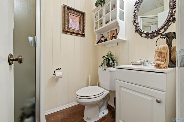 bathroom featuring hardwood / wood-style floors, vanity, wood walls, and toilet