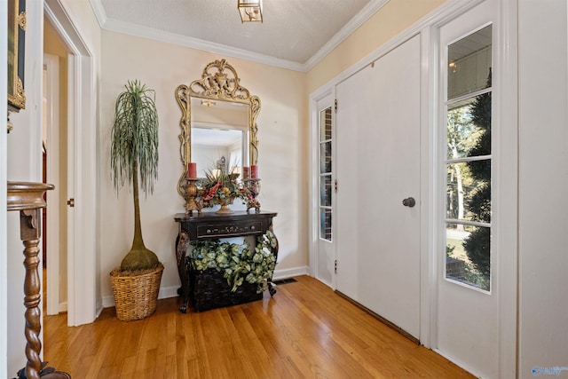 entryway featuring a textured ceiling, light hardwood / wood-style flooring, a wealth of natural light, and crown molding