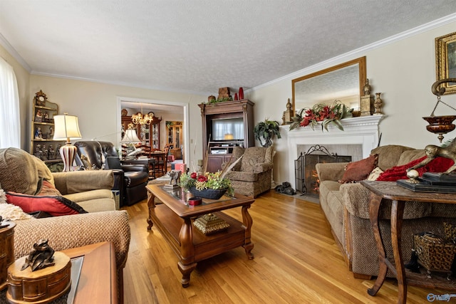 living room with crown molding, an inviting chandelier, a textured ceiling, and light wood-type flooring