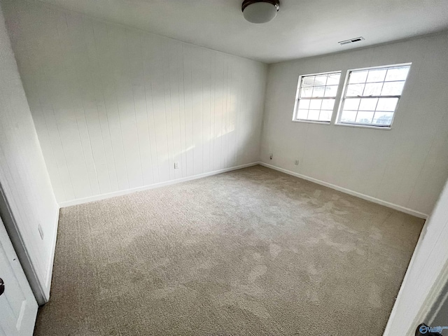 unfurnished room featuring carpet floors, visible vents, and baseboards