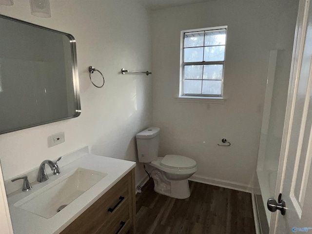 bathroom with toilet, wood finished floors, vanity, baseboards, and walk in shower