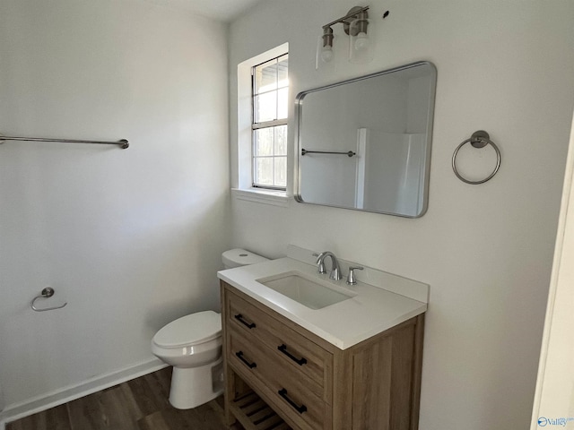 bathroom featuring baseboards, vanity, toilet, and wood finished floors
