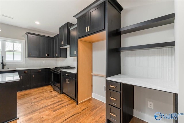 kitchen with gas range, sink, tasteful backsplash, and light wood-type flooring