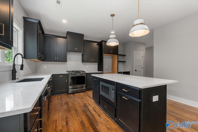 kitchen featuring sink, light stone counters, a center island, appliances with stainless steel finishes, and pendant lighting