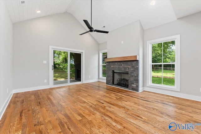 unfurnished living room featuring ceiling fan, plenty of natural light, light wood-type flooring, and a fireplace