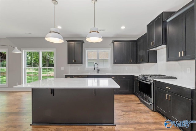 kitchen featuring decorative backsplash, decorative light fixtures, stainless steel gas range, and a kitchen island