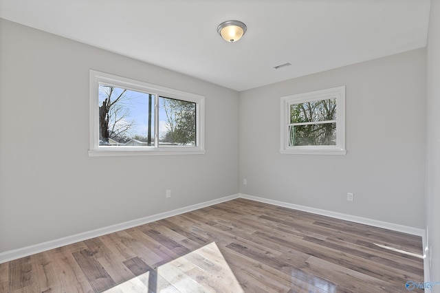 spare room featuring visible vents, light wood finished floors, and baseboards