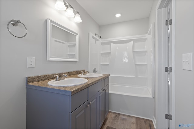 full bathroom with double vanity, a sink, shower / bathing tub combination, and wood finished floors