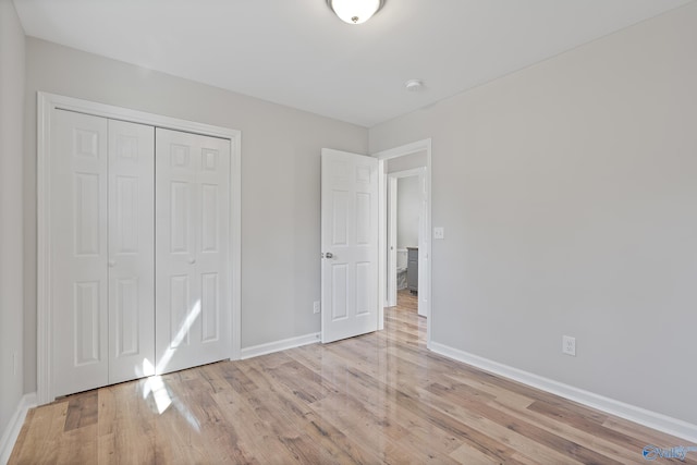 unfurnished bedroom with a closet, baseboards, and light wood finished floors