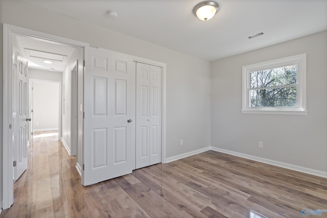 unfurnished bedroom featuring a closet, visible vents, light wood-style flooring, and baseboards