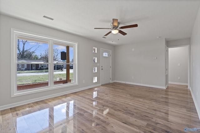 unfurnished living room featuring light wood-style floors, visible vents, ceiling fan, and baseboards