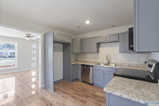 kitchen with appliances with stainless steel finishes, light countertops, a sink, and gray cabinetry