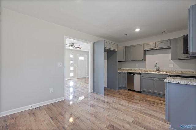 kitchen featuring a sink, light countertops, stainless steel dishwasher, and gray cabinetry